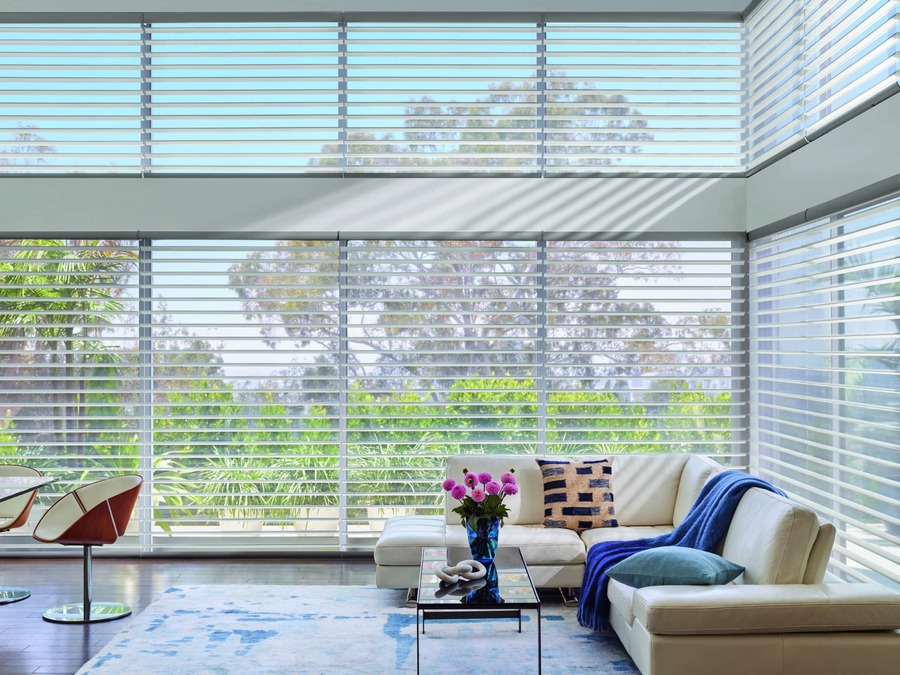 A living area with Hunter Douglas motorized blinds on floor-to-ceiling windows.