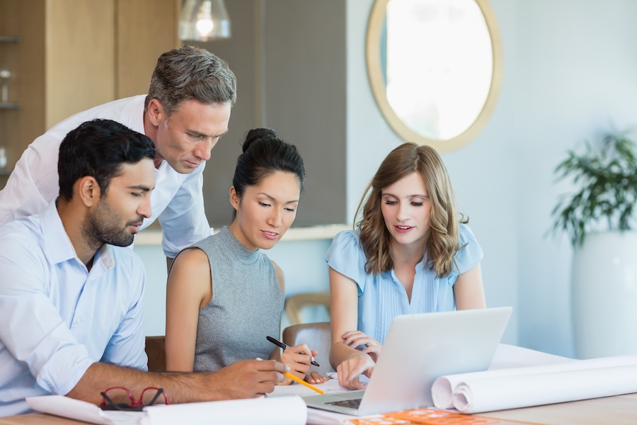A group discusses building plans while looking at a laptop.