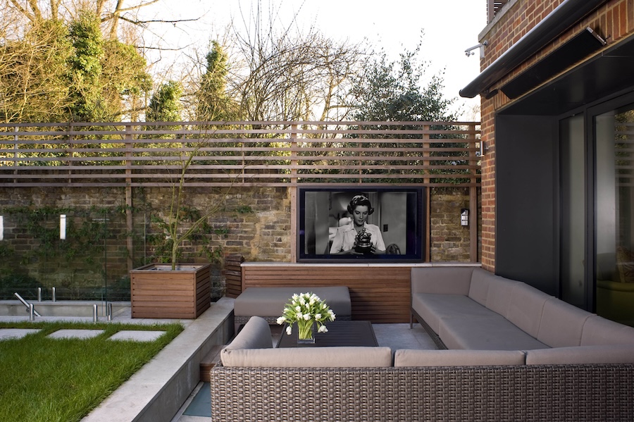 A small patio near grass maximized with seating and a TV.