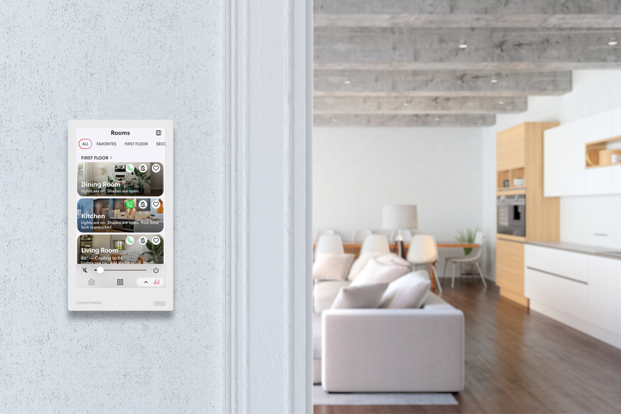 A home’s living area with a touchscreen on a wall displaying the Crestron Home platform.