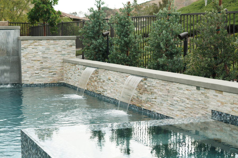 Luxury backyard pool with landscape speakers integrated into the environment.